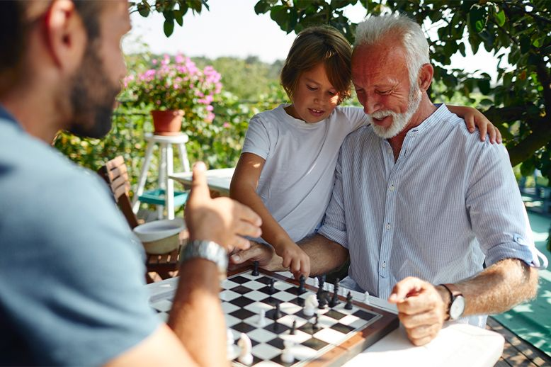 three-generations-of-male-family-playing-chess-together-in-page