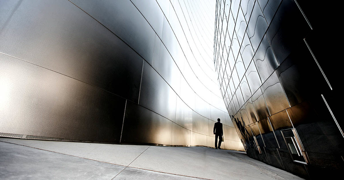 Man walking along curve between two modern buildings