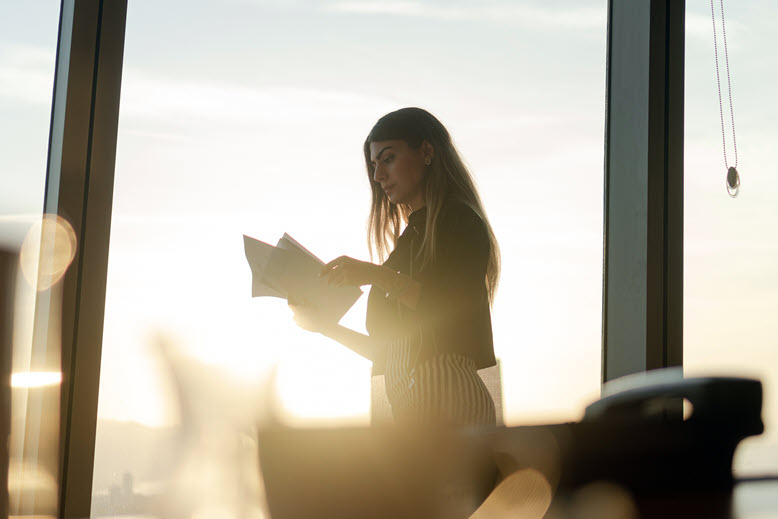 businesswoman-looking-at-papers-in-office-with-sunset