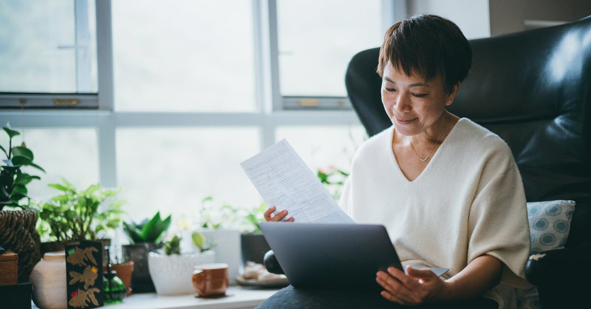Senior Asian woman checking bills with computer