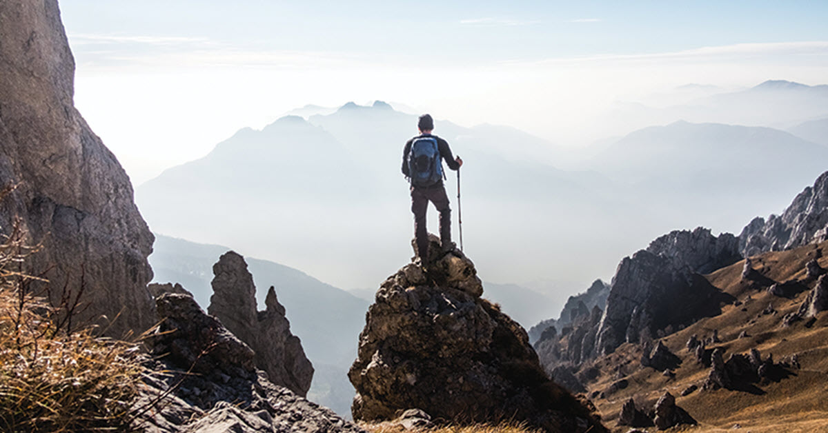 Hiker looking out over mountain range representative of looking out for your legacy.