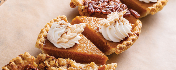 Pumpkin pie with whipped cream, topped with a holly leaf cookie, pecan, and apple pie displayed in a diagonal line. RBC Wealth Management logo overlayed in the right corner.