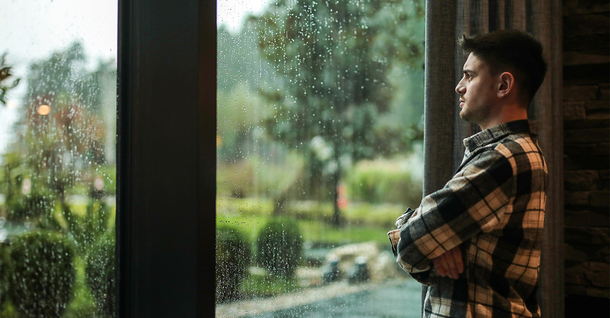 Man looking out the window on a rainy day