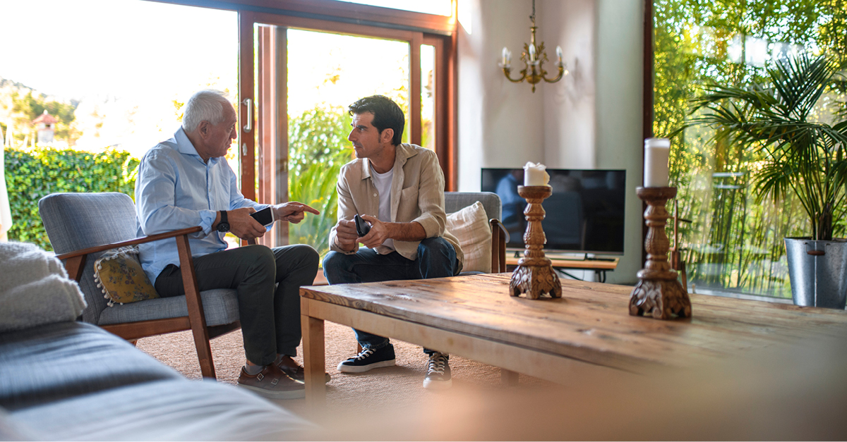 Senior father adult son talking in living room