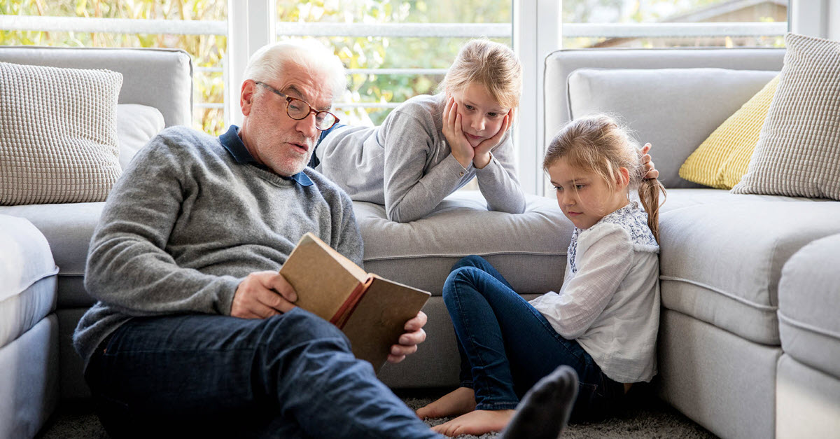 Grandfather reaching to his grandchildren on a couch