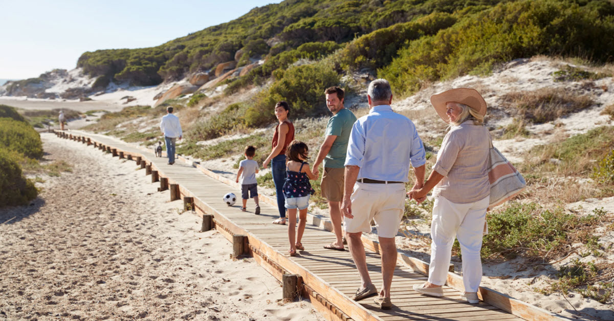 Grandparents with their grandchildren walking on a beach boardwalk
