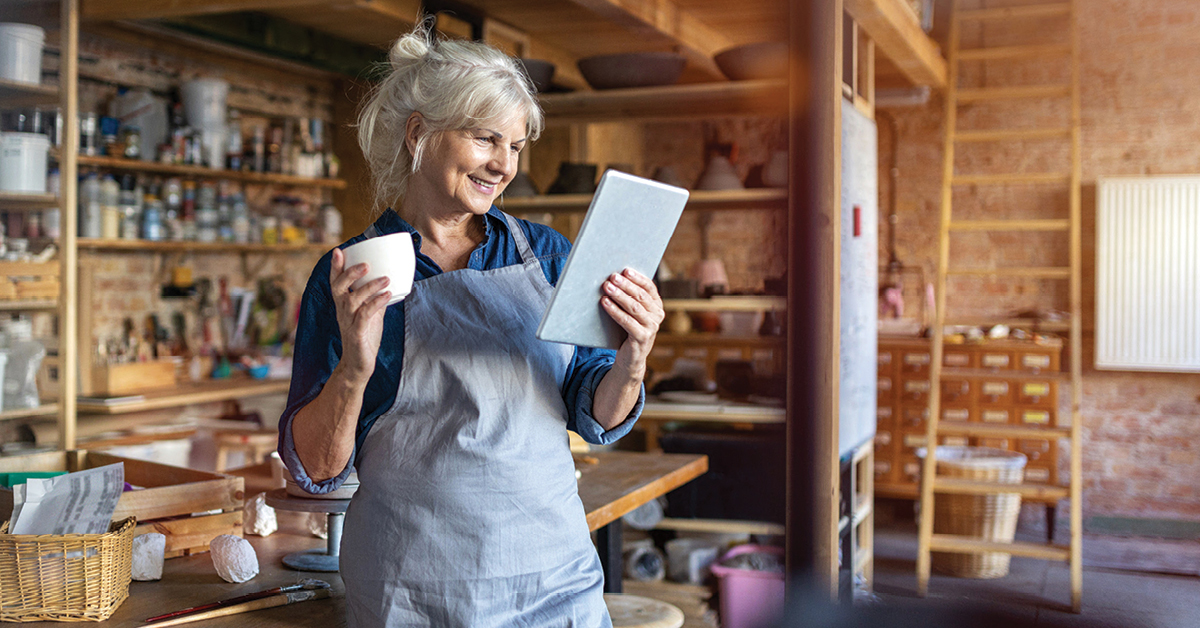 Older woman in her ceramic studio looking at a tablet