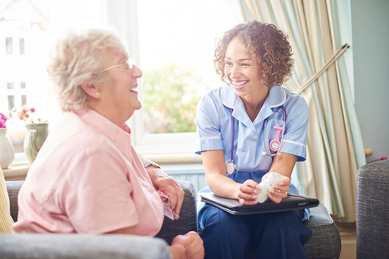 Elderly woman laughing with nurse in page.