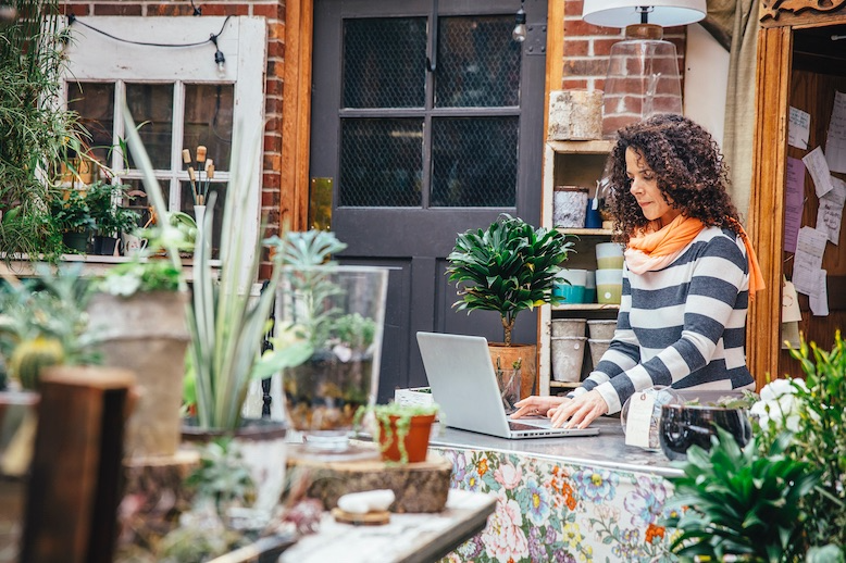 Woman working outdoors in home office surrounded by plants