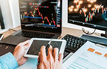 Man looking at charts on computer and tablet