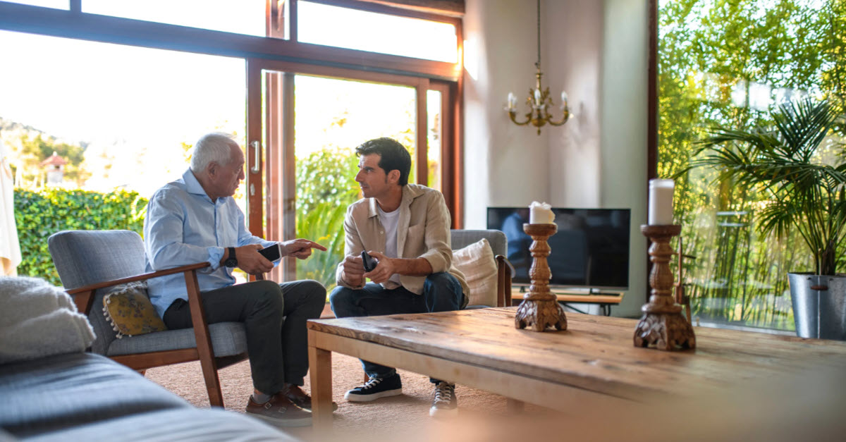 Father and son talking about finances in their living room 