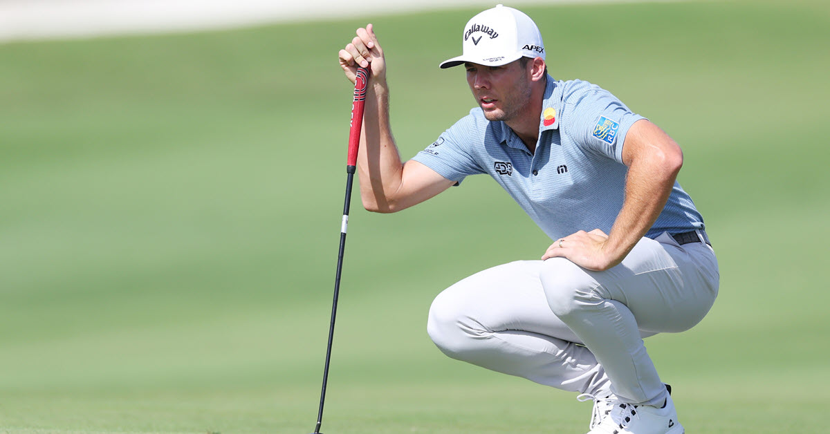 Sam Burns crouching on golf course