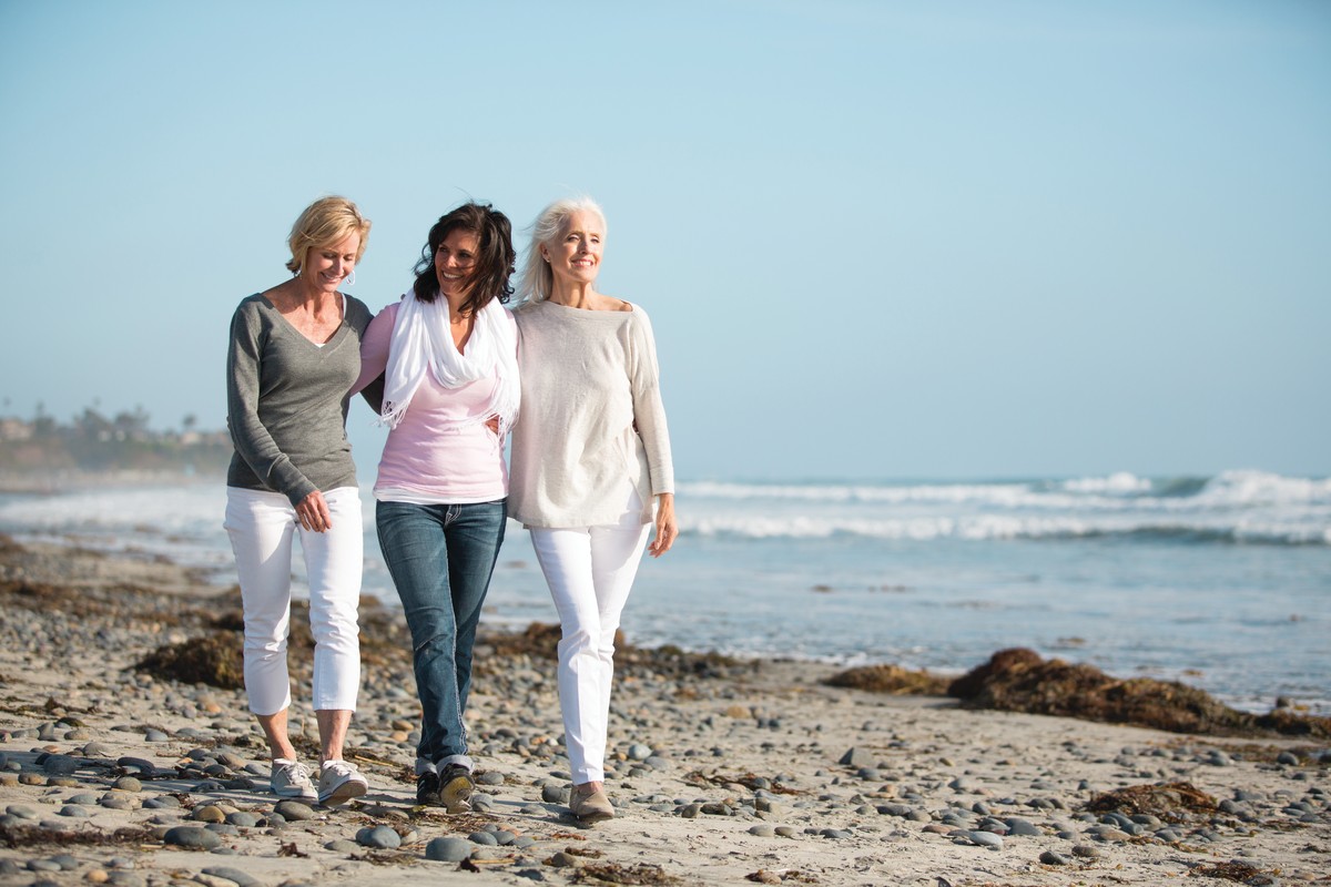 three-women-strolling-on-beach-with-arms-around-each-other
